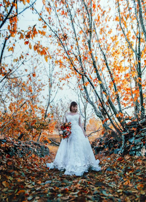 a woman in a wedding dress standing in a forest