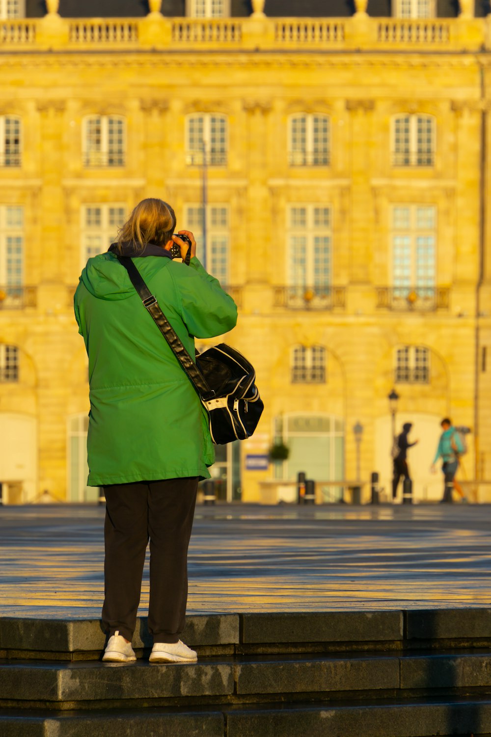 a woman in a green coat talking on a cell phone