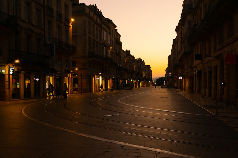 a city street at night with people walking on the sidewalk