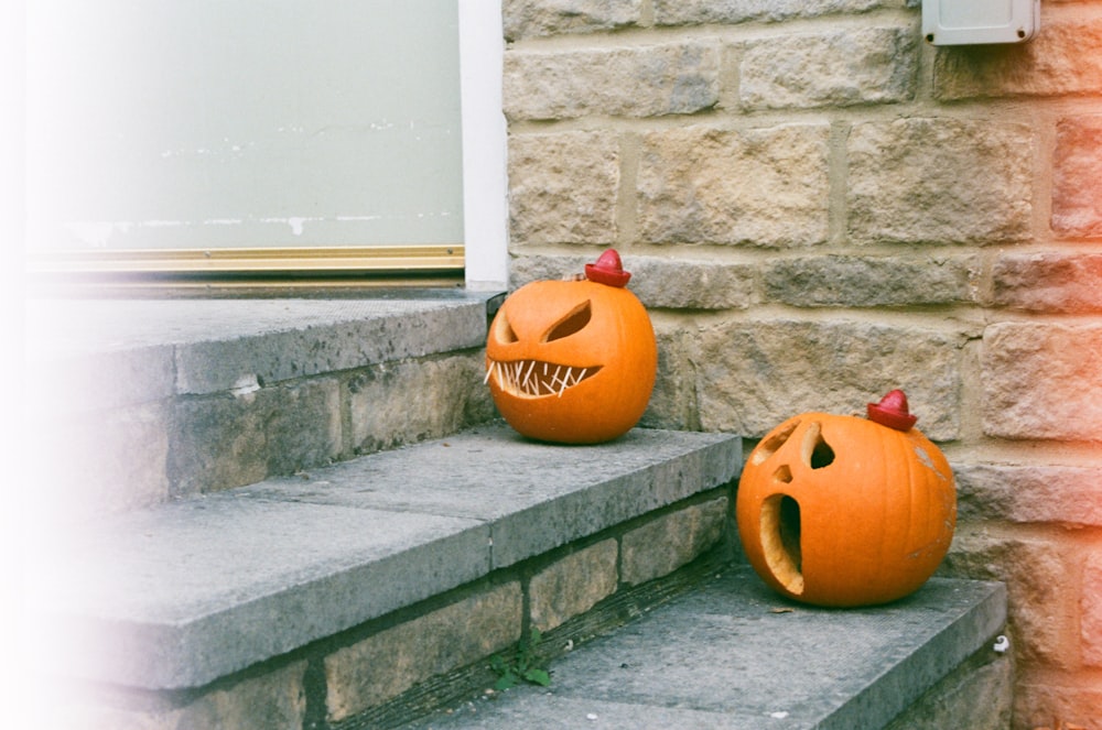 two carved pumpkins sitting on the steps of a house