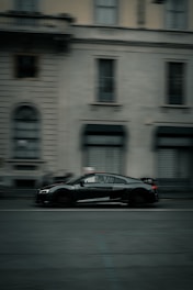 a black sports car driving down a city street