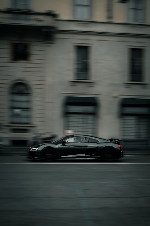 a black sports car driving down a city street
