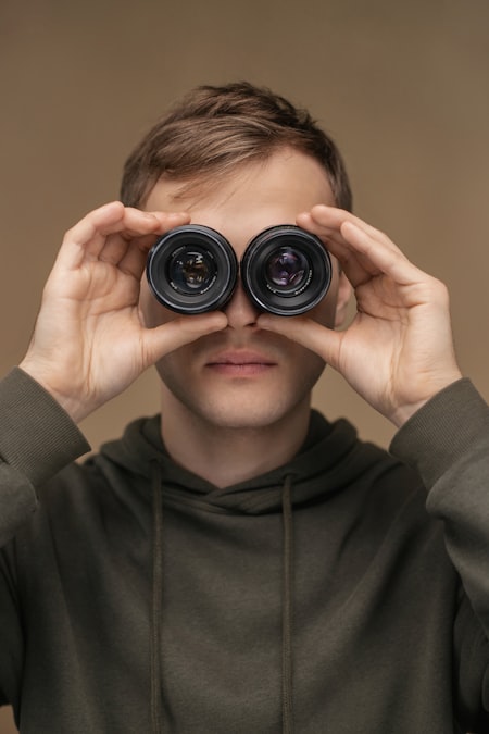 A person looking through binoculars, representing the practice of watching what a competitor's customers say in public