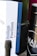 A close-up view of a box with the label 'Italian Pavilion' and some text related to the Mostra Internazionale d'Arte Cinematografica di Venezia, featuring a color-coded design. Beside the box, a dark cylindrical container is partially visible with the text 'MAÌA GARDA DOC' on it.