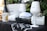 A still life arrangement featuring bottles of Maïa sparkling wine, two white wine glasses with the Maïa logo, a white bucket, and a cap with the word 'Signorvino' on it. The items are set against a backdrop of greenery, creating an elegant and sophisticated atmosphere.