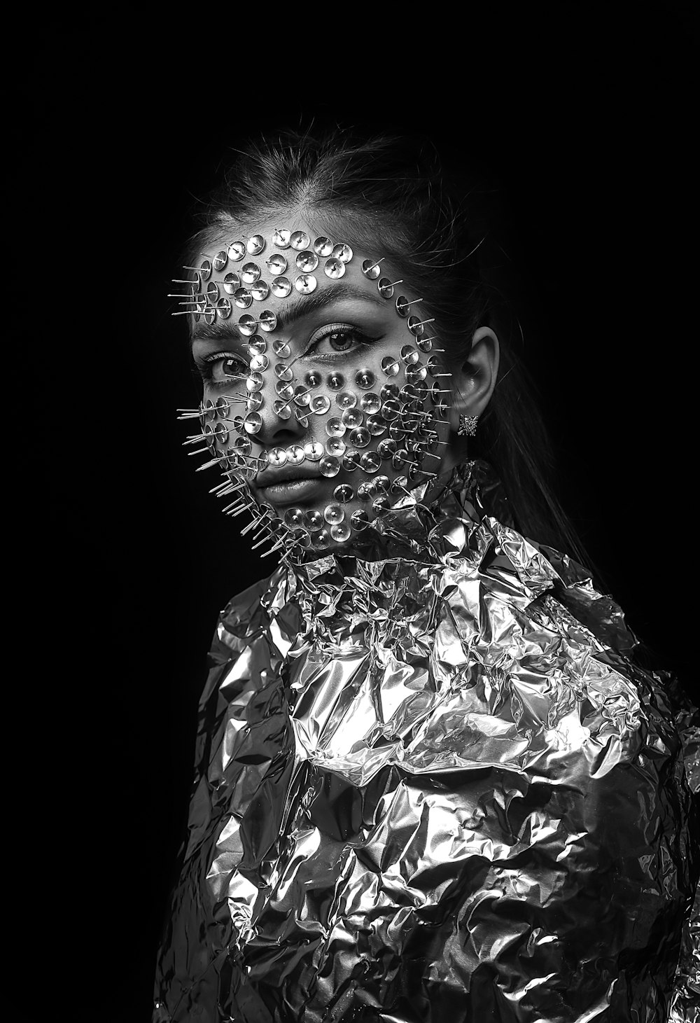 a woman in a metallic jacket with spikes on her face