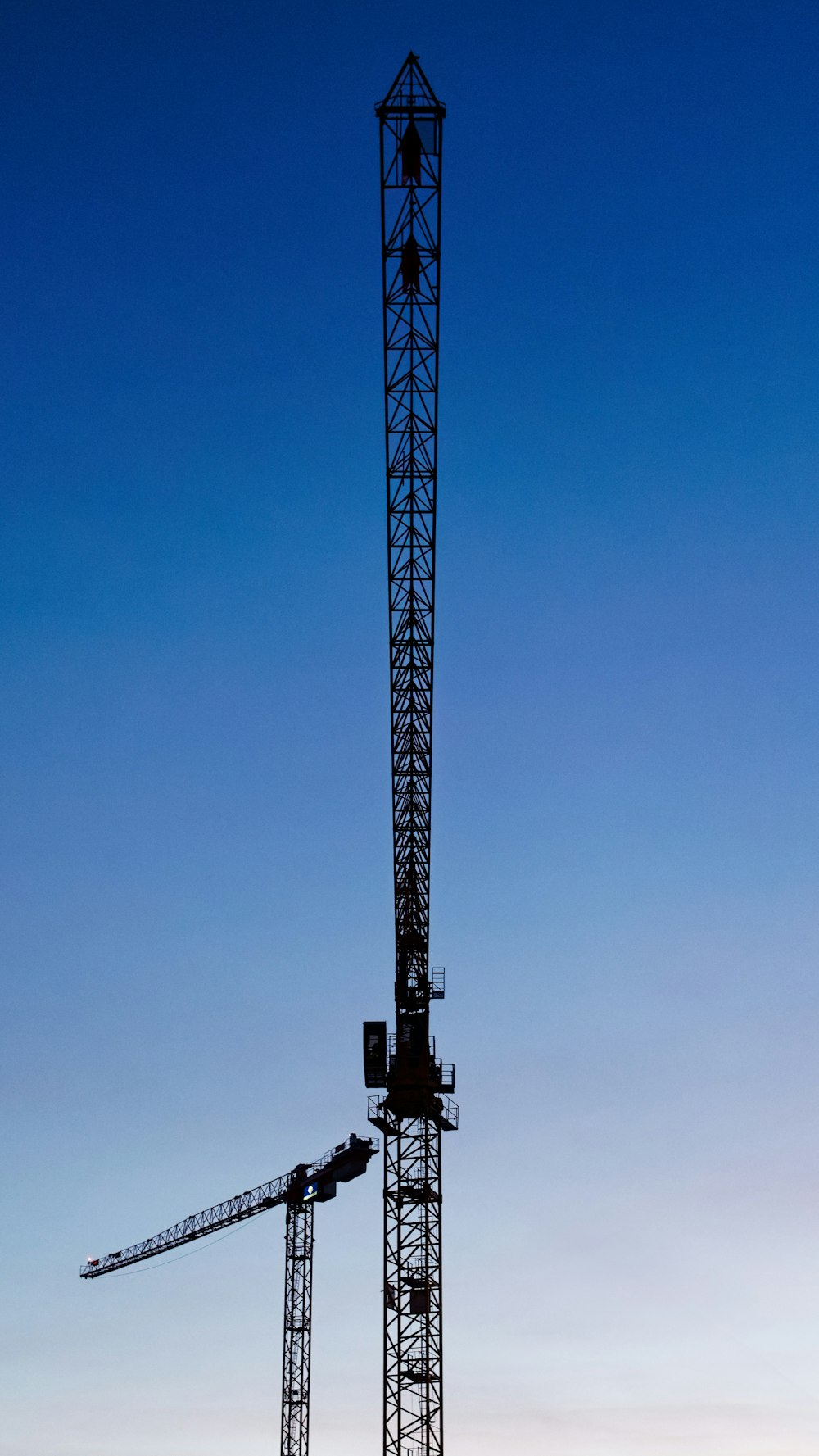 a tower crane is silhouetted against a blue sky
