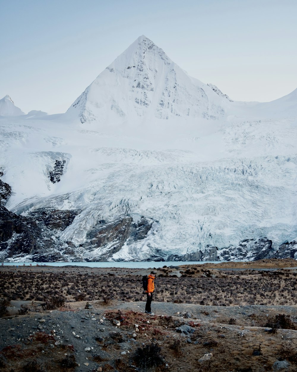 uma pessoa em pé na frente de uma montanha coberta de neve