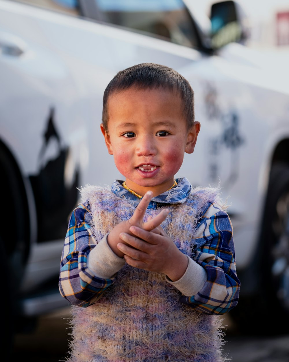 a young boy standing in front of a white car