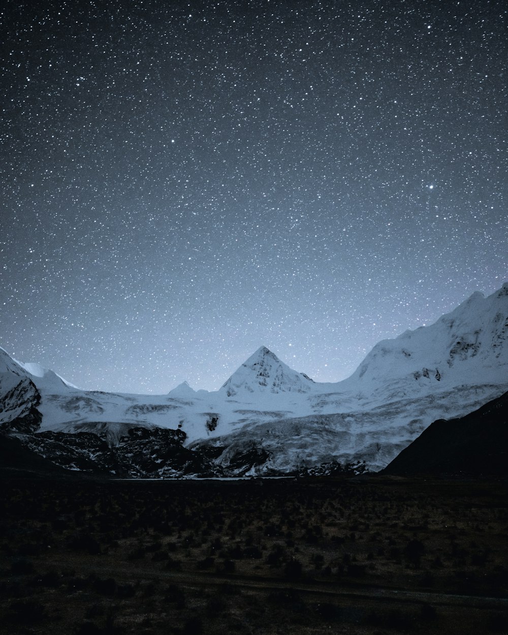 a snowy mountain range with stars in the sky