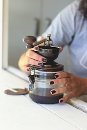 a woman holding a coffee pot on top of a counter