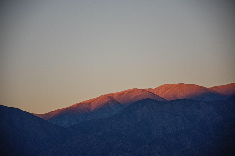 a plane flying over a mountain range at sunset