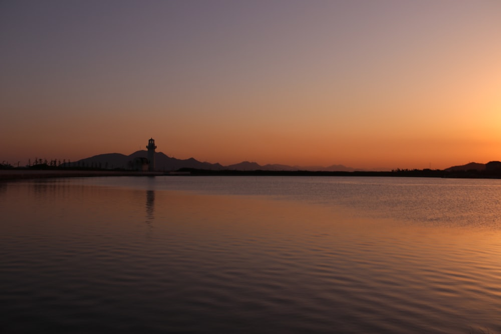 the sun is setting over a lake with mountains in the background