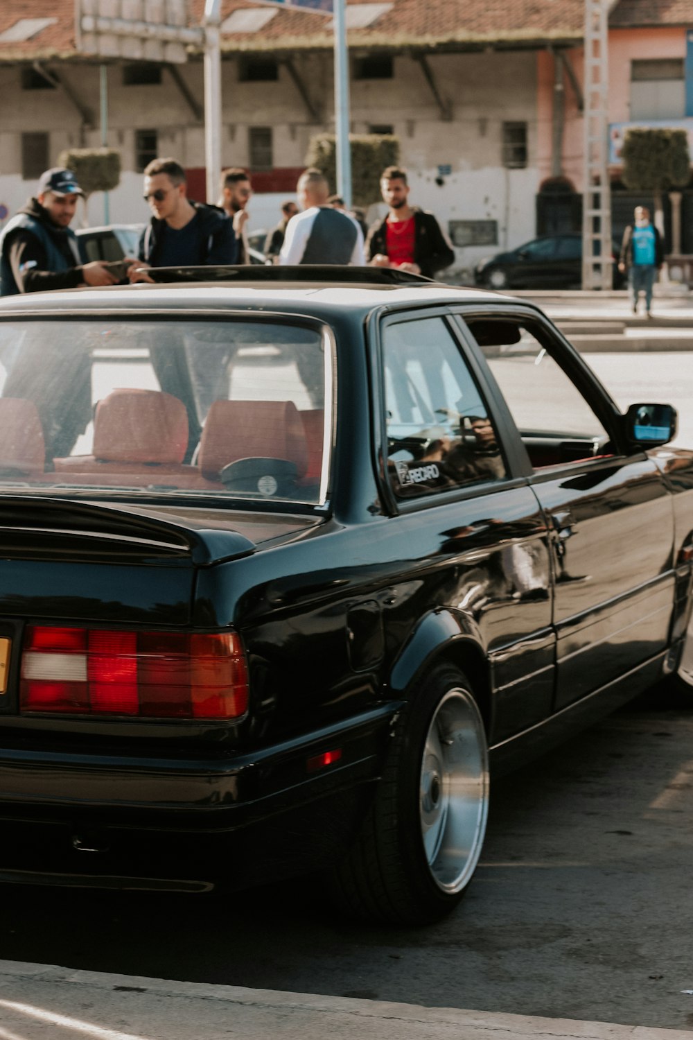 a group of people standing around a black car