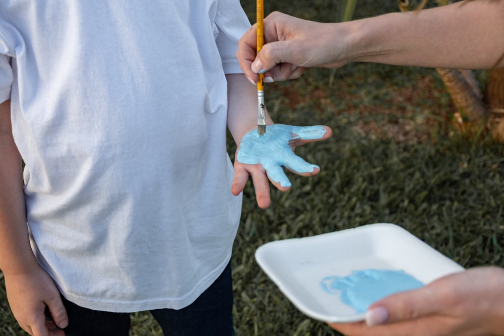 a person holding a paintbrush and a hand with a blue substance on it