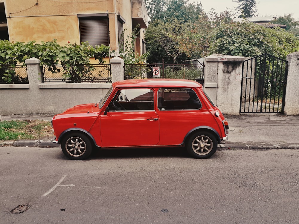 a small red car parked on the side of the road
