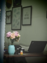 A serene workspace with a laptop and floral arrangements.
