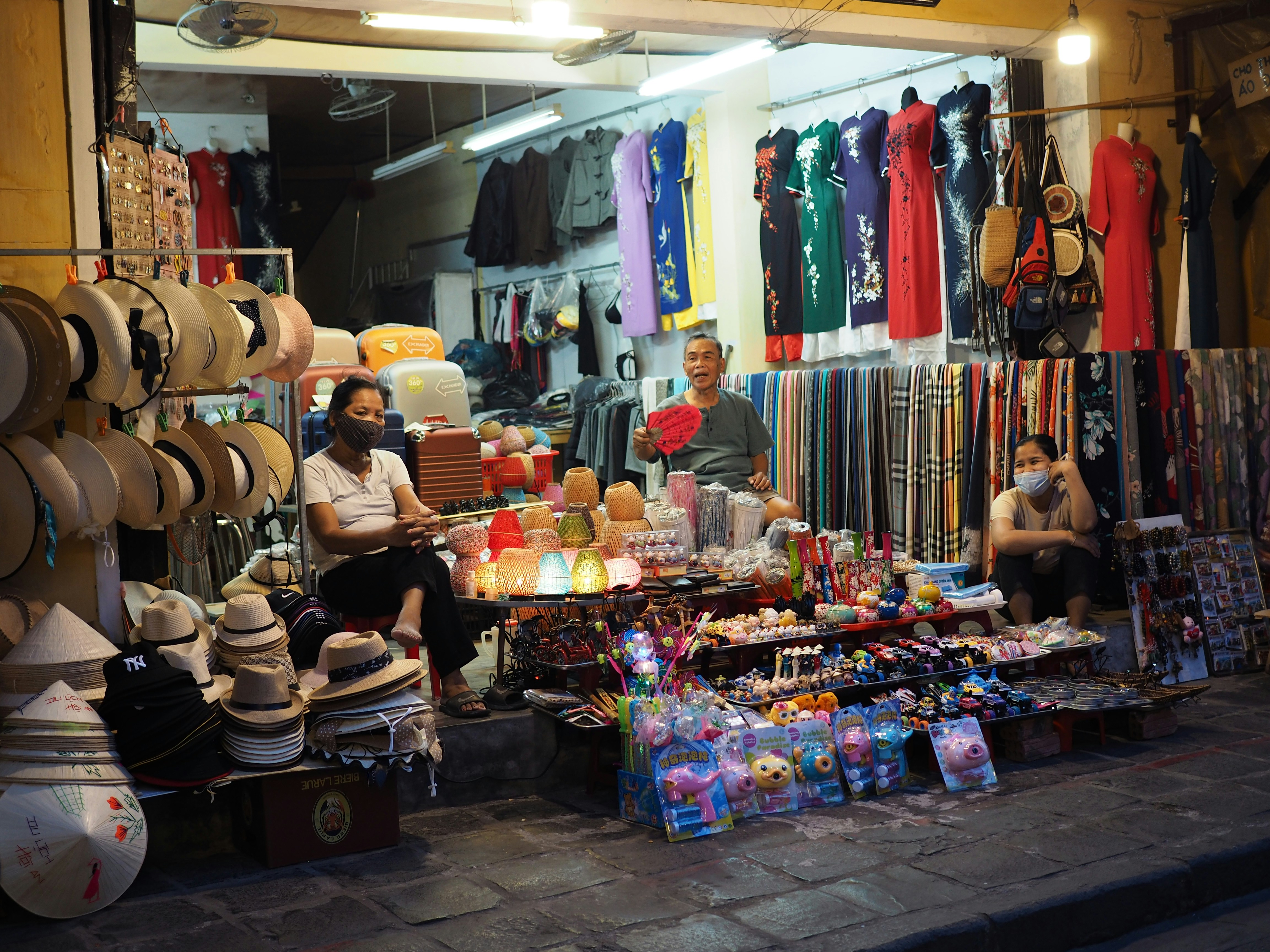 a man sitting in front of a store filled with hats