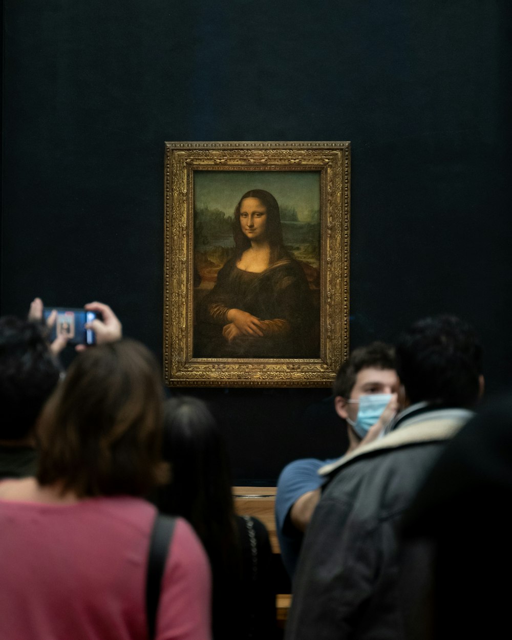 a group of people taking pictures of a painting