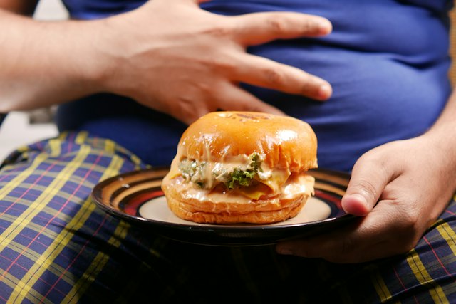 Person sitzt vor einem Teller mit Essen und mag nicht zugreifen