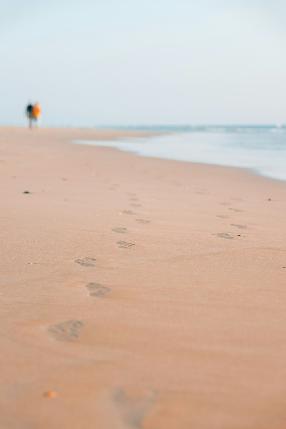 a person walking along a beach with footprints in the sand