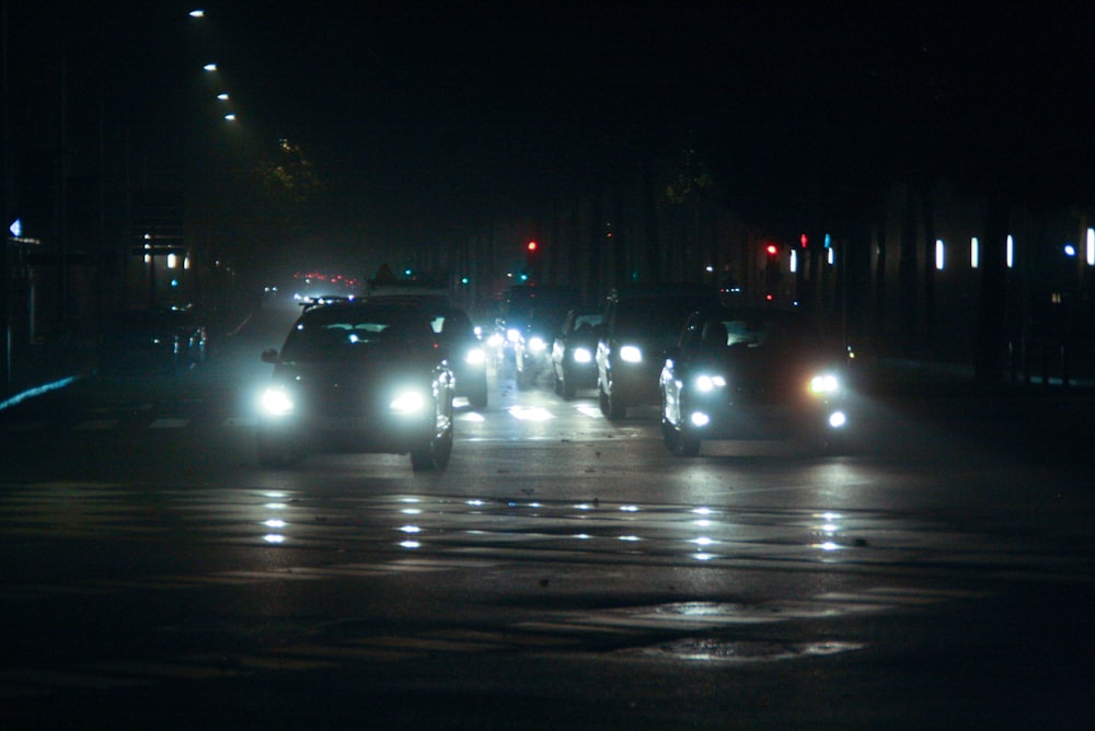 a group of cars driving down a street at night