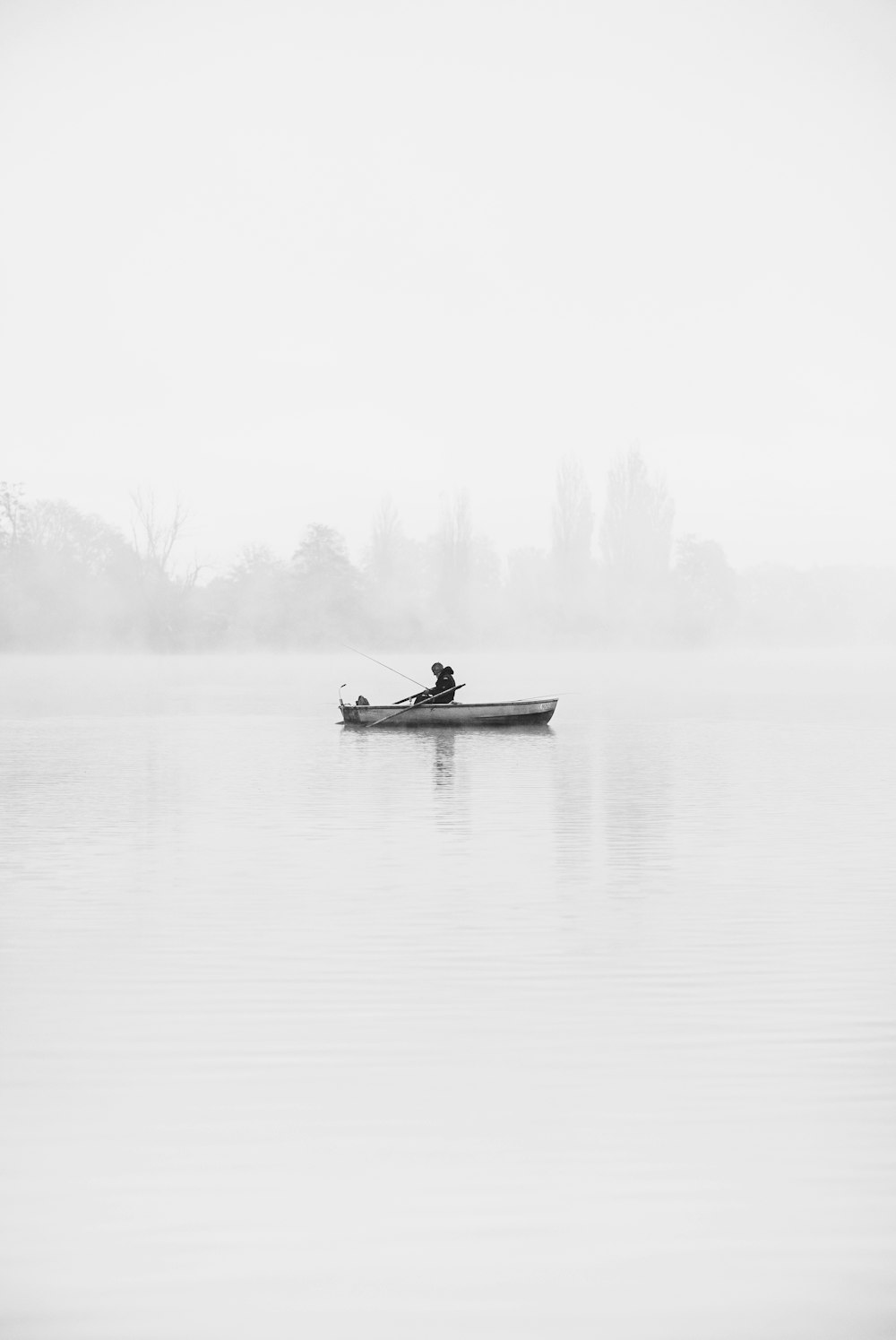 a man in a row boat on a foggy lake