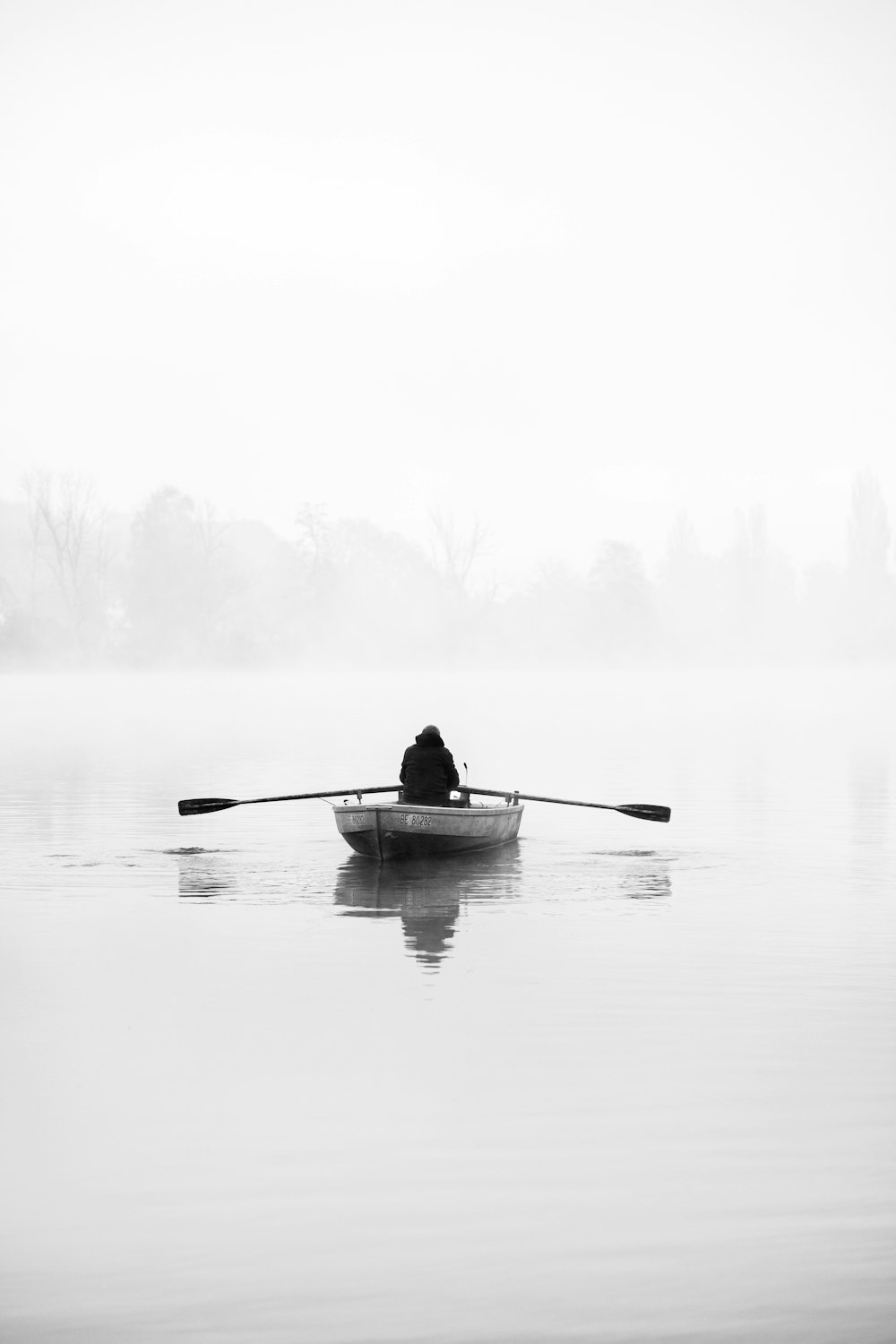 Eine Person in einem Ruderboot auf einem nebligen See