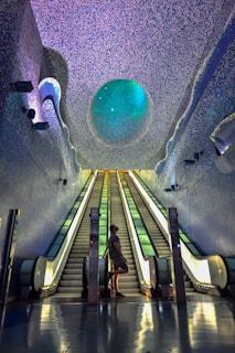 a man and a woman standing at the bottom of an escalator