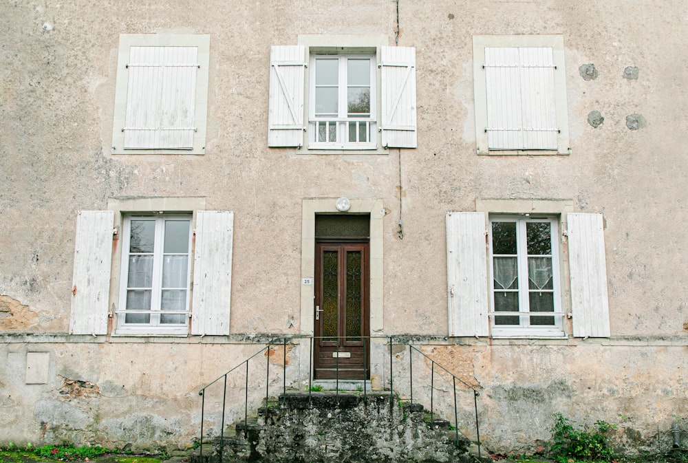 a building with white shutters and a brown door