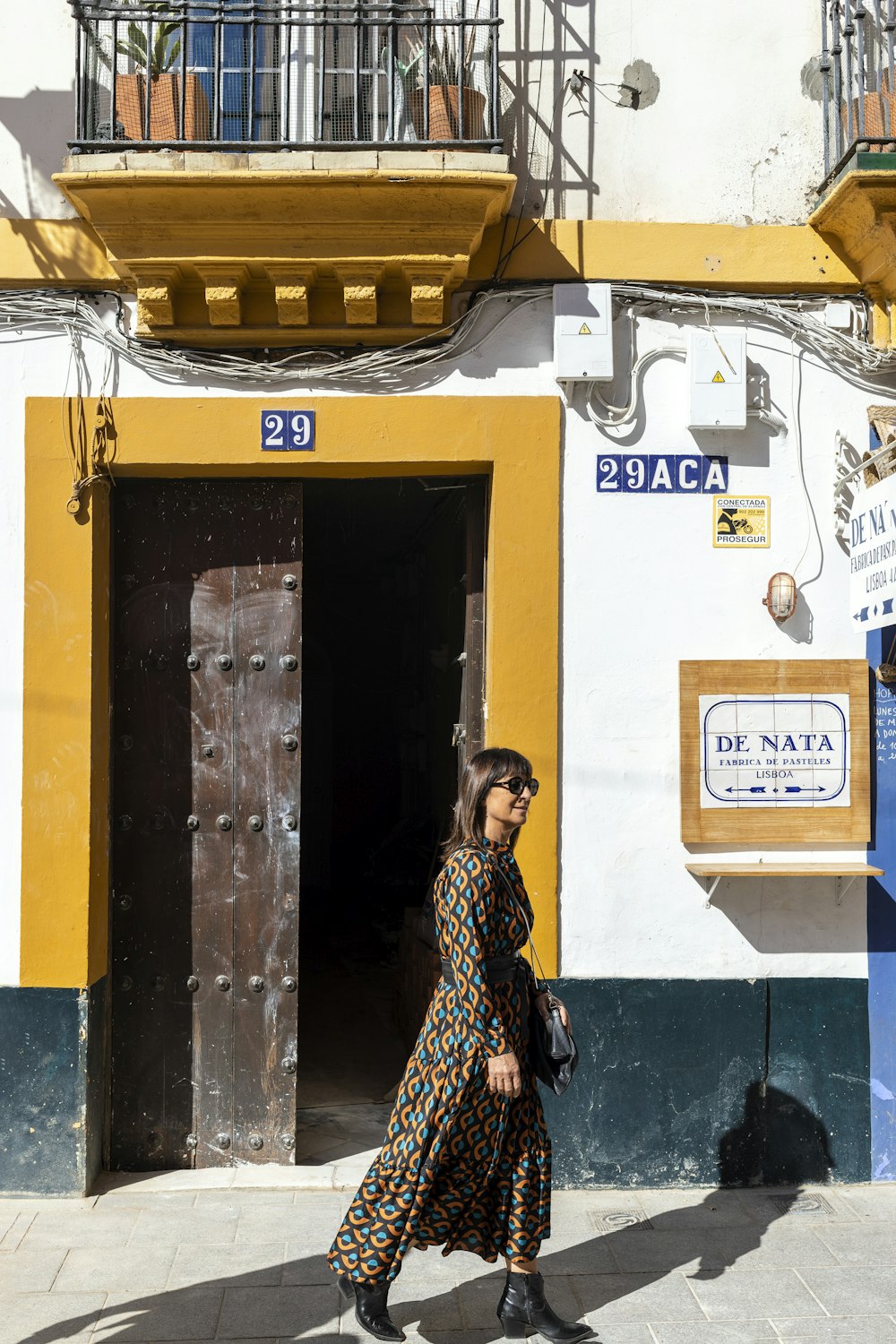a woman walking down a street past a yellow and white building