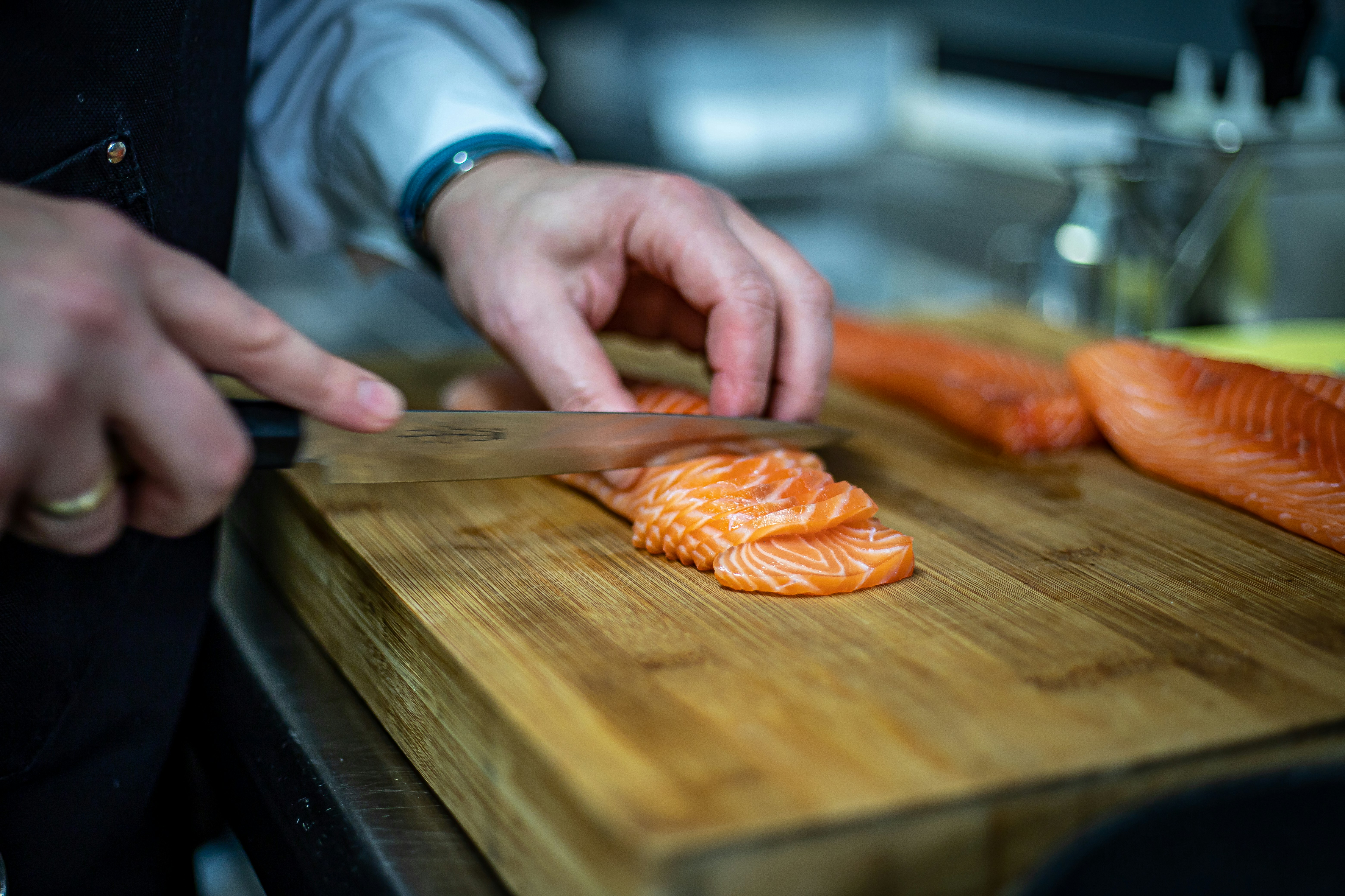 Chef slicing salmon fish on wooden board