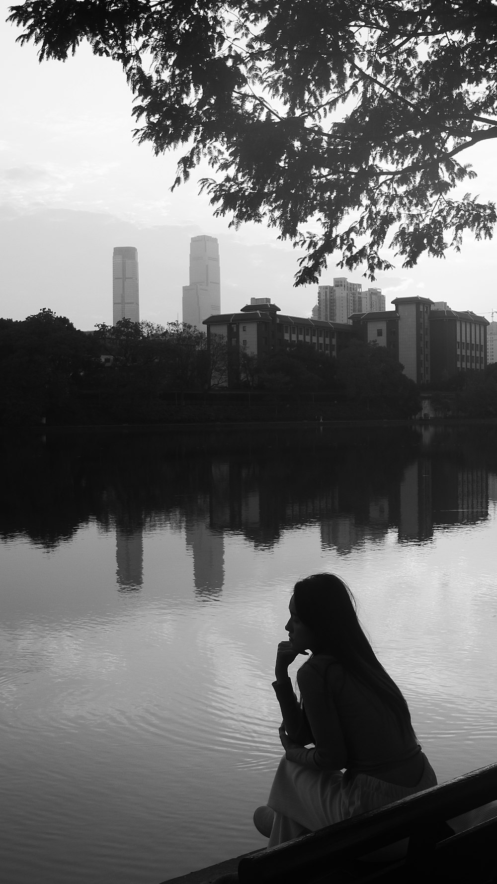 a woman sitting on a bench next to a body of water