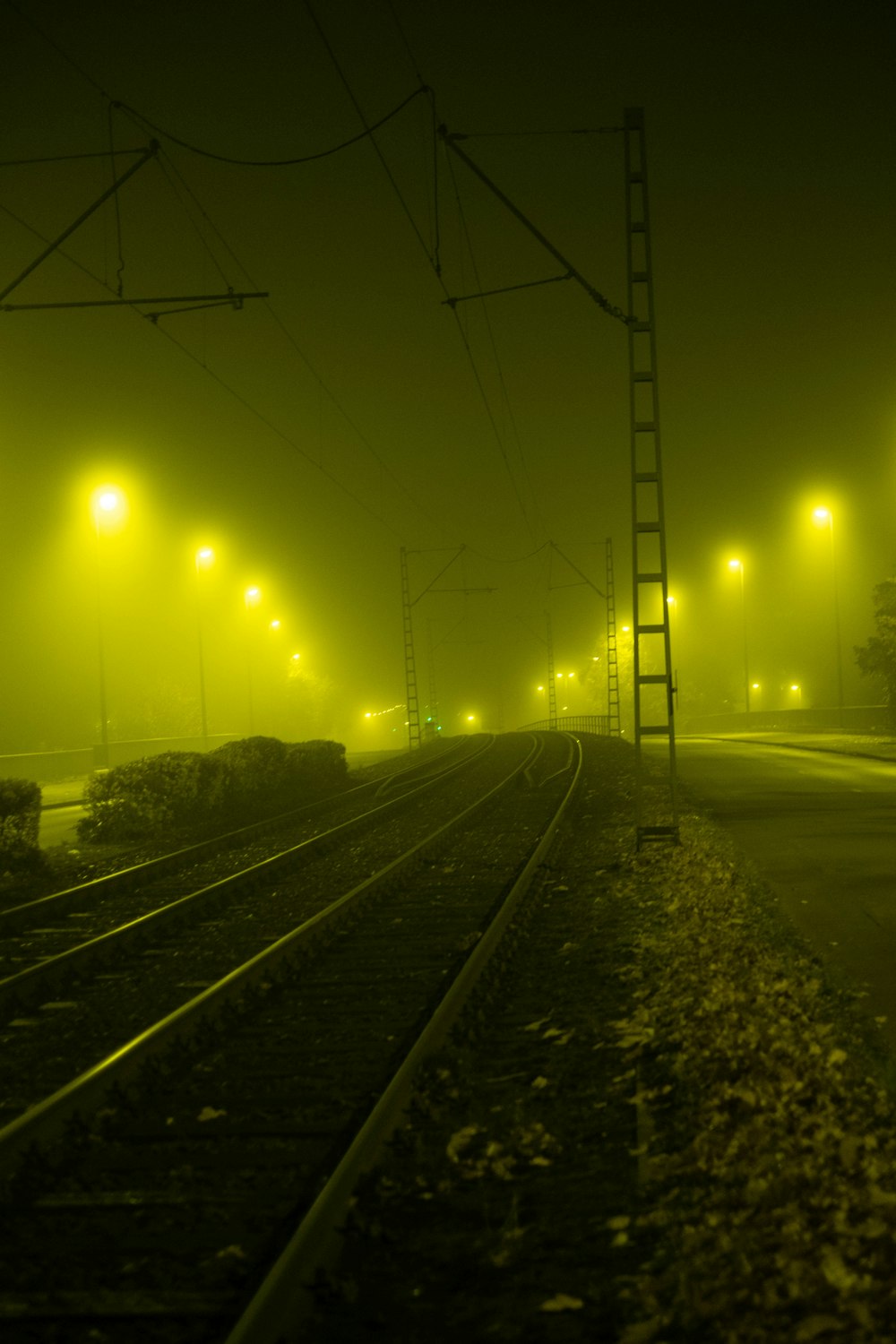 a foggy train track at night with street lights