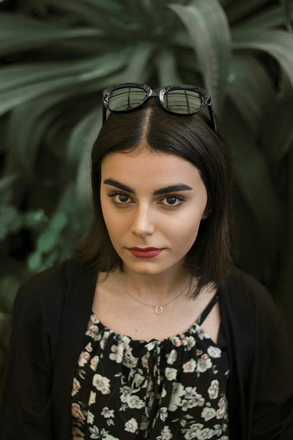 a woman with dark hair and glasses on her head