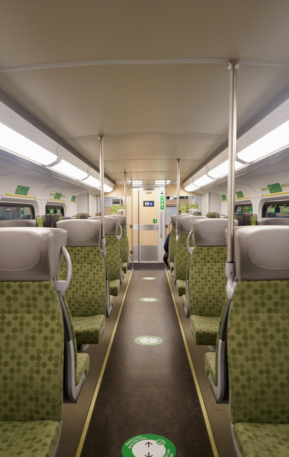 an empty train car with green seats and a clock