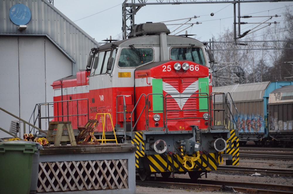 a red train traveling down train tracks next to a building