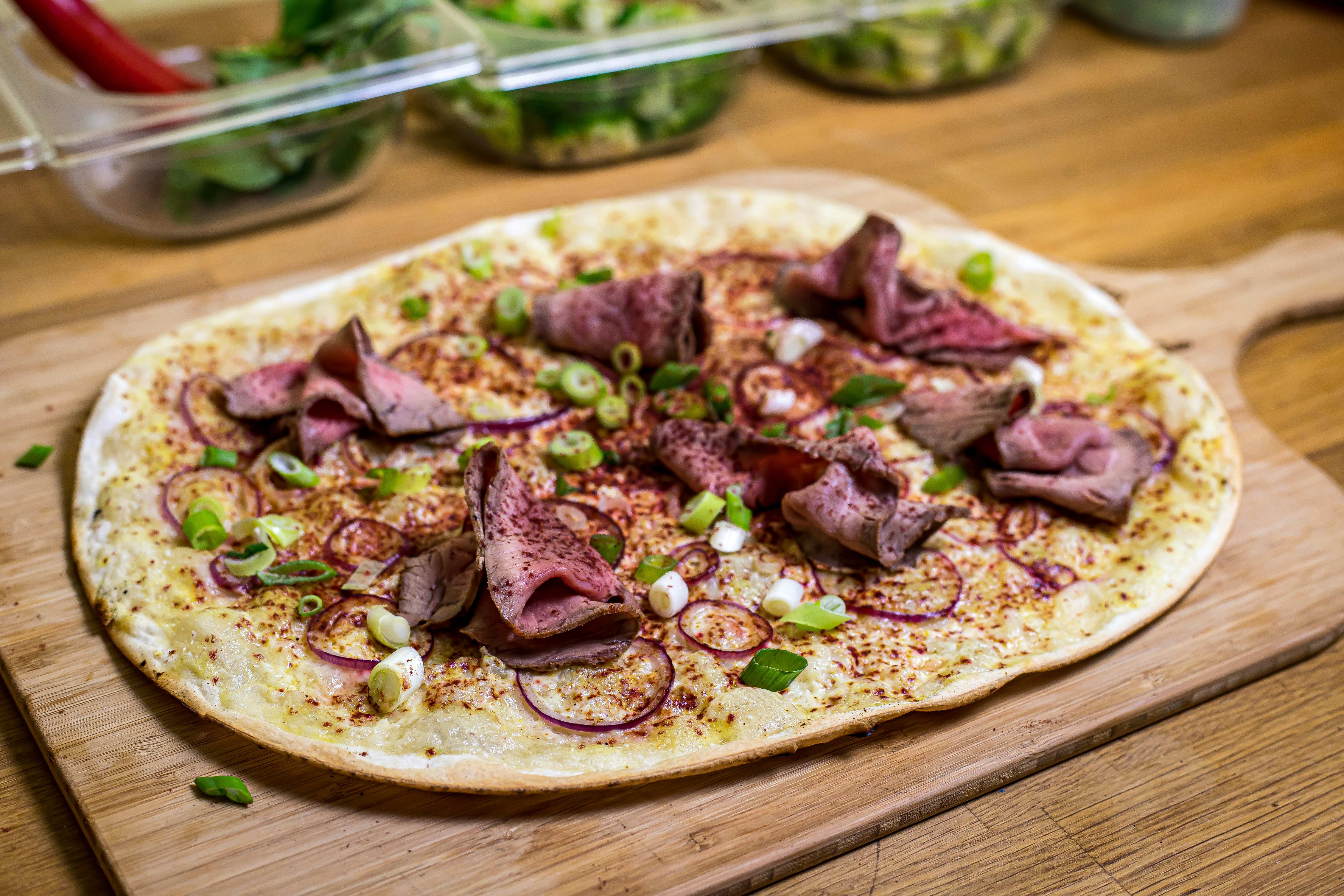 Una pizza sentada encima de una tabla de cortar de madera