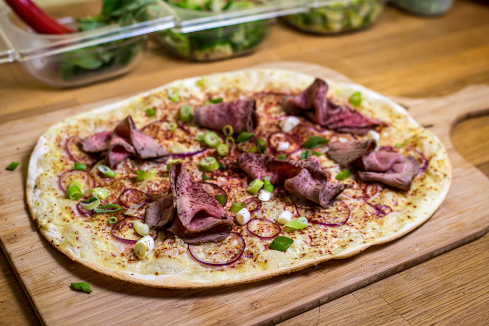 Thin crisp tart with cream and toppings on a wooden board