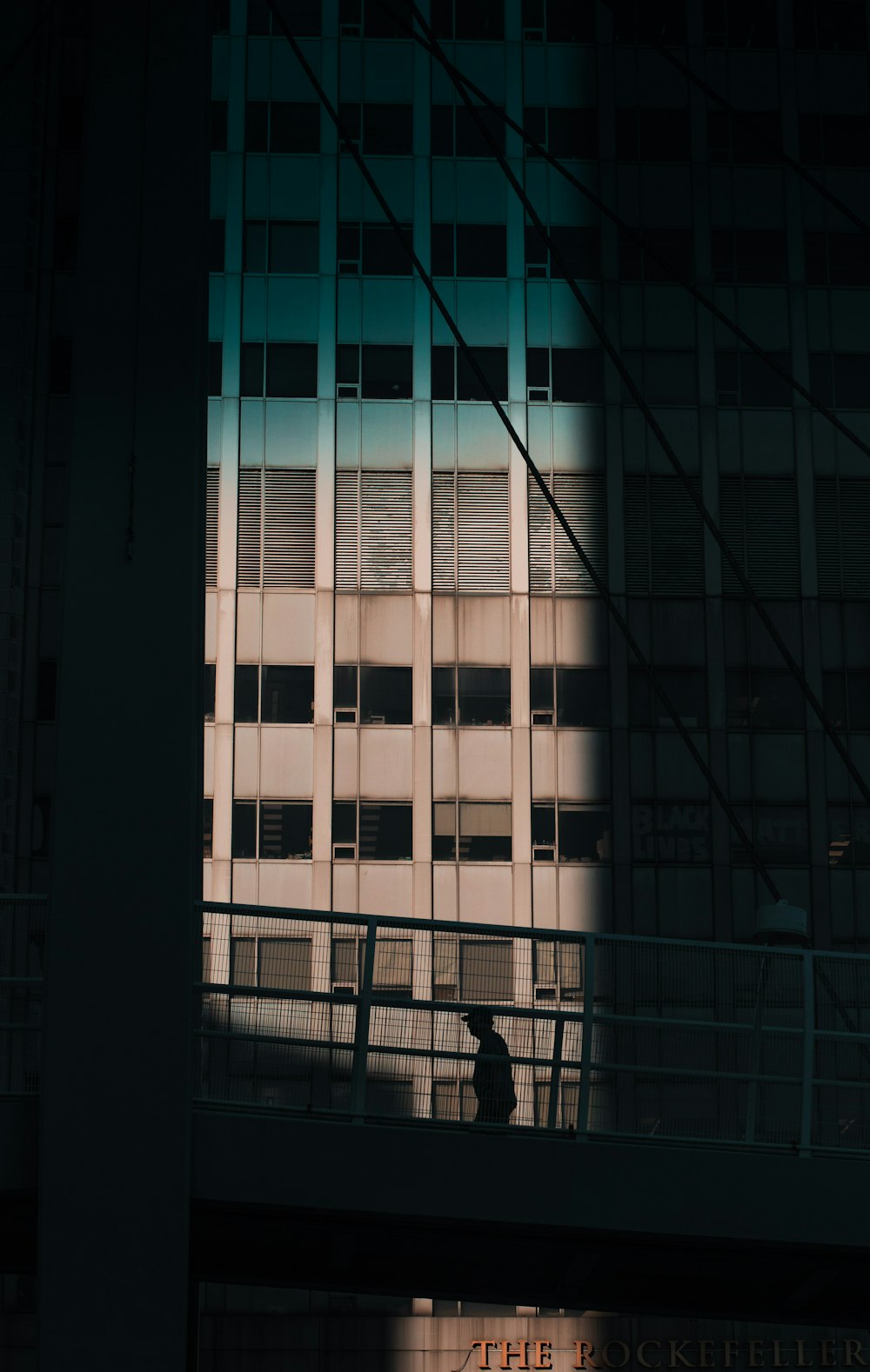 a person walking across a bridge in front of a tall building