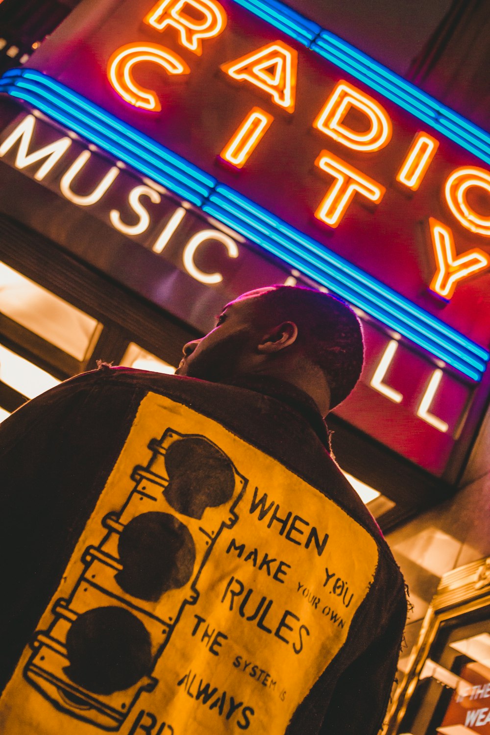 a man standing in front of a neon sign