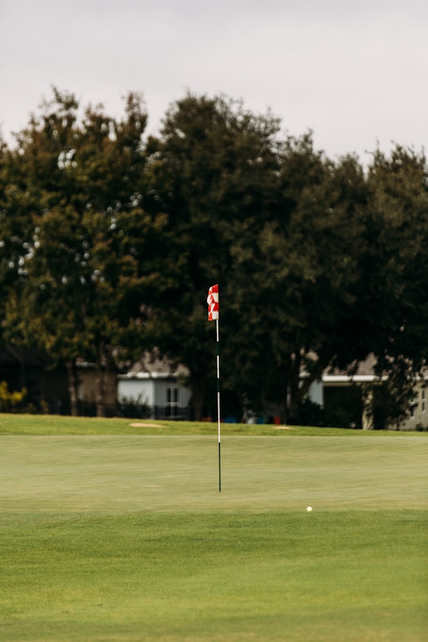 Golf course green with flag pin in the distance, showing the target both rangefinders and GPS watches measure