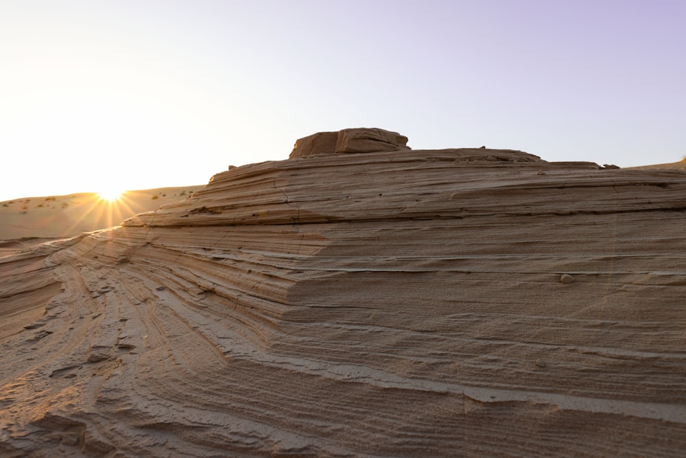 the sun is setting over a rocky outcropping