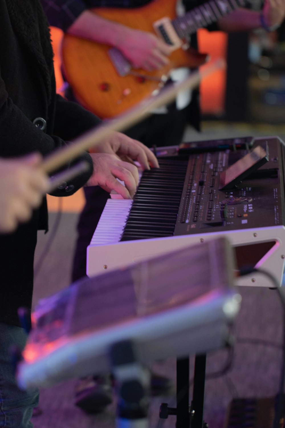 a person playing a keyboard with a guitar in the background