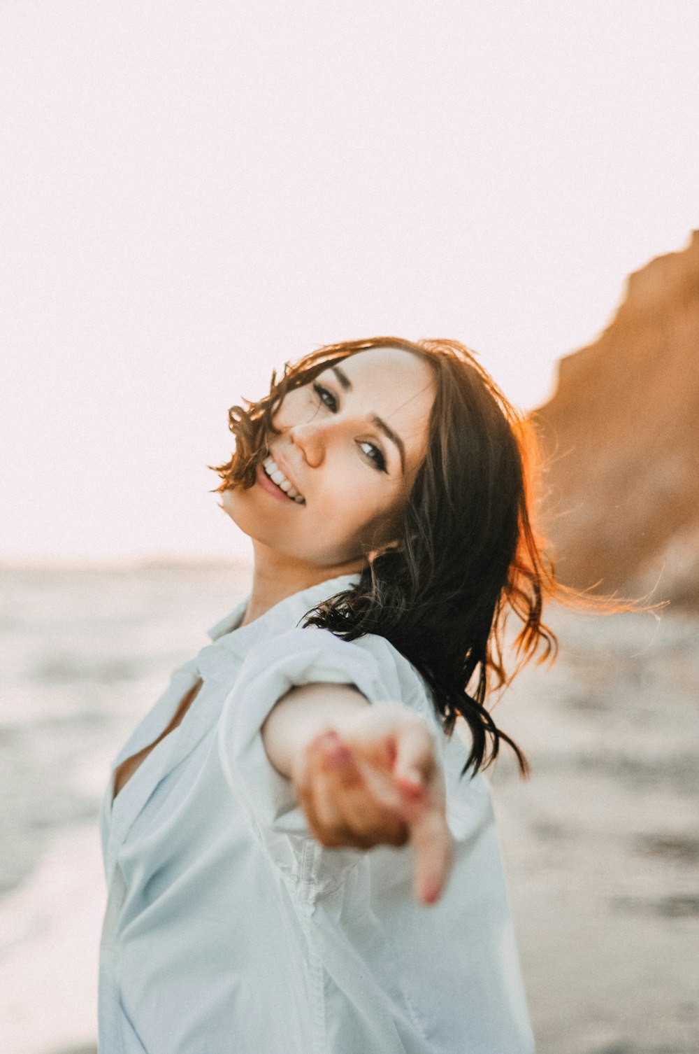 a woman pointing at something while standing on a beach