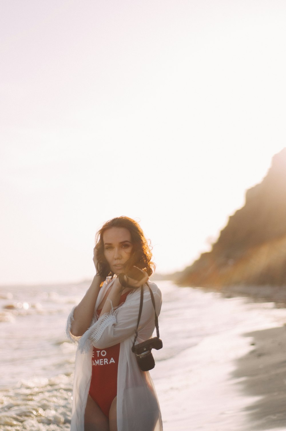 a woman standing on a beach talking on a cell phone