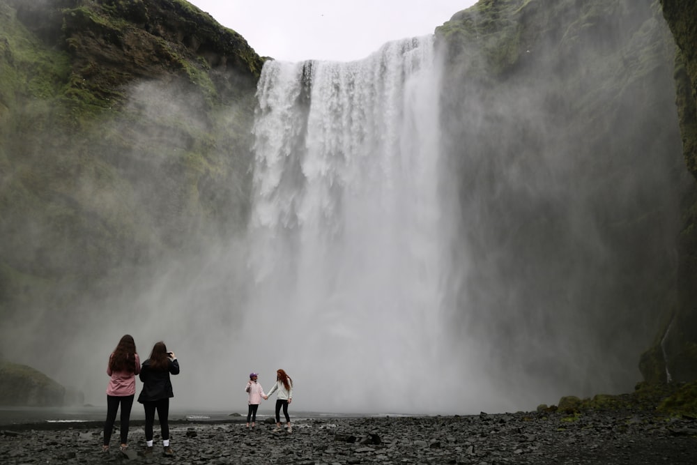 a group of people standing in front of a waterfall