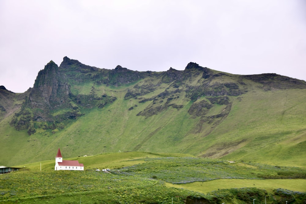 a small church on a grassy hill with a mountain in the background