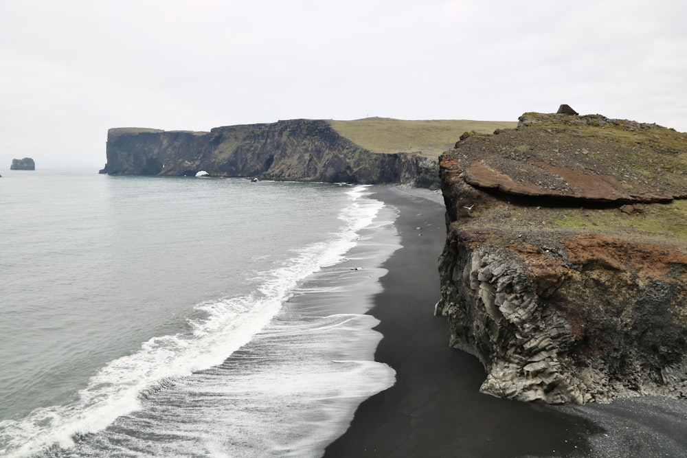 a black sand beach next to a cliff