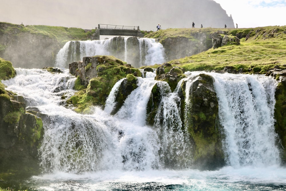 a group of people standing at the base of a waterfall